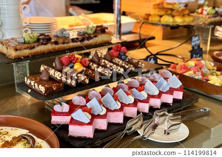 The portions of chocolate, red and different cakes with berries on a black stands on the counter of the restaurant. Close-up 114199814