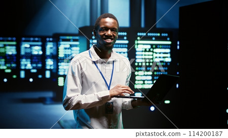 Technician making sure high tech facility data servers are appropriately equipped to provide redundancy, automatic failover and rapid reconfiguration of clusters to minimize failure of individual rigs 114200187