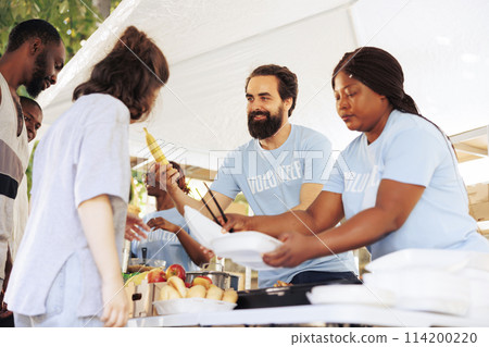 Hunger relief initiative providing essential items to the hungry and less fortunate. Friendly humanitarian aid team distributes food, offering support to poor, homeless people and refugees. 114200220