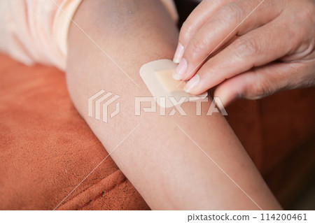 applying adhesive bandage on a child feet  114200461