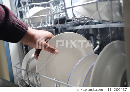 A young woman opens takes out clean white utensils. A young woman opens takes out clean white utensils. 114200487