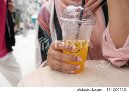 orange juice with ice cube in a plastic container  114200520