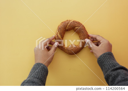 top view of hand holding Turkish Bagel Simit on table top view of hand holding Turkish Bagel Simit on table 114200564
