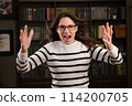 Portrait of an angry woman boss with glasses in the office looks at the camera and screams 114200705