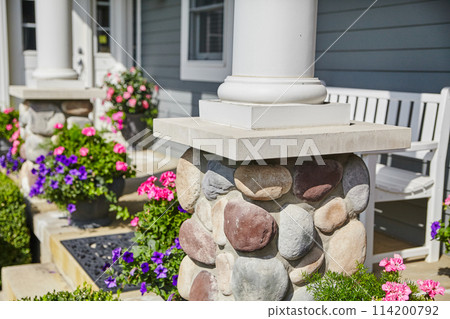 Sunny Residential Entrance with Stone Column and Flower Arrangements 114200792
