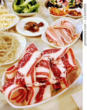 Communal Hot Pot Dining with Sliced Beef and Vegetables, Eye-Level View Communal Hot Pot Dining with Sliced Beef and Vegetables, Eye-Level View 114200936