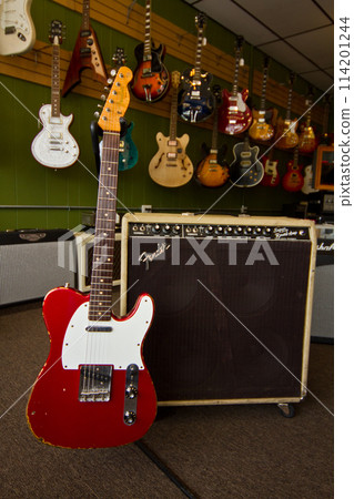 Red Electric Guitar Display in Music Store with Vintage Amplifier 114201244