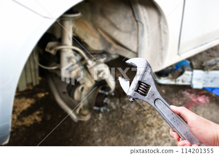 An adjustable spanner or adjustable wrench in the hand of an auto mechanic An adjustable spanner or adjustable wrench in the hand of an auto mechanic 114201355