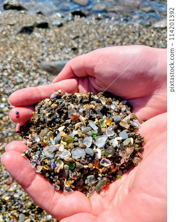 Handheld Sea Glass and Pebbles on Beach Background Handheld Sea Glass and Pebbles on Beach Background 114201392