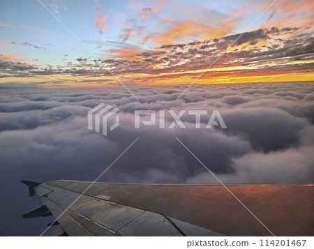 Aerial Sunset Glow Over Clouds with Airplane Wing 114201467