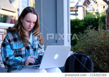 teenage girl with a laptop sitting on the porch of the house. She watching the news doing homework online conference backpack folder water bottle pencil ordinary people real life teenage girl with a laptop sitting on the porch of the house. She watching the news doing homework online conference backpack folder water bottle pencil ordinary people real life 114202389