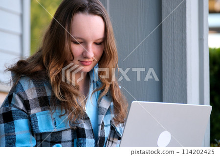 teenage girl with a laptop sitting on the porch of the house. She watching the news doing homework online conference backpack folder water bottle pencil ordinary people real life 114202425