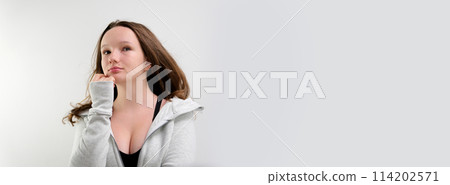 Woman in a black shirt with a direct look of disappointment on a white background Woman in a black shirt with a direct look of disappointment on a white background 114202571