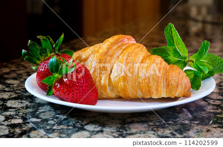 on a plate two delicious appetizing fresh croissants with strawberries and mint appetizing food purchases Grocery wheat flour butter advertisement of any product related to leisure and food place 114202599