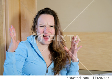 Redhead woman wearing easter rabbit ears at home annoyed and frustrated shouting with anger, crazy and yelling with raised hand, anger concept 114202683