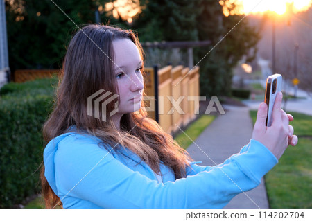 Happy American hipster teen girl blogger influencer recording vlog holding looking at camera. woman travel vlogger shooting blog, streaming, video calling on urban city street, headshot. 114202704