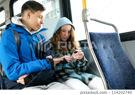 two teenagers in blue clothes sit on a bus Canada Vancouver hoods autumn winter spring tracksuits use a mobile phone search for geolocation travel travelers real life two teenagers in blue clothes sit on a bus Canada Vancouver hoods autumn winter spring tracksuits use a mobile phone search for geolocation travel travelers real life 114202740