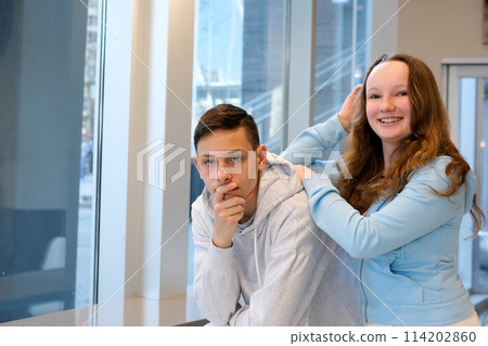 Cheerful young couple two friends in pastel blue casual clothes, woman hugging man, standing behind him, looking  114202860