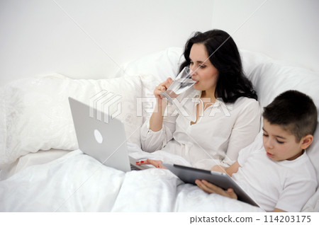 diet weight loss woman drinks water in bed while working on computer son plays tablet proper nutrition Healthy way of life coronavirus quarantine spend time Alone with yourself in circle of loved ones 114203175