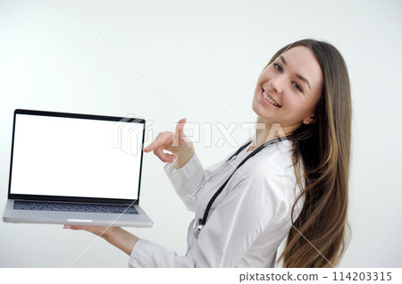 Happy doctor holding empty blank in hands. Female doctor showing a clipboard with blank paper. Close-up of a female doctor with lab coat and holding blank clipboard 114203315