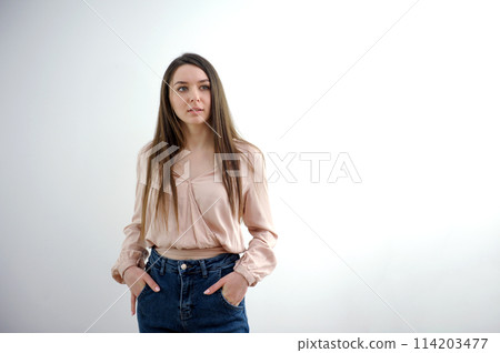 Close-up young slender woman holding her hands at waist of her jeans on white studio background. Close-up young slender woman holding her hands at waist of her jeans on white studio background. 114203477