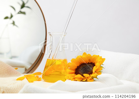 Template for beauty product promotion with sunflower as the main ingredient, a erlenmeyer flask with yellow liquid stand on counter covered by cotton towel next to a sunflower and some flower petals Template for beauty product promotion with sunflower as the main ingredient, a erlenmeyer flask with yellow liquid stand on counter covered by cotton towel next to a sunflower and some flower petals 114204196