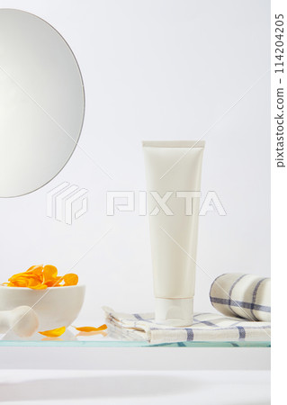 Sunflower products theme in white tones with a blank label tube stand on a checkerboard towel next to a mortar with sunflower petals inside. Front view photo with mockup for advertising Sunflower products theme in white tones with a blank label tube stand on a checkerboard towel next to a mortar with sunflower petals inside. Front view photo with mockup for advertising 114204205
