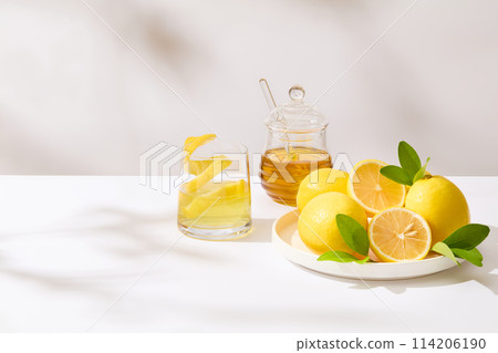 A round dish of fresh lemon placed next a honey jar and a glass of lemon juice on the right side of photo. The left side is blank for presentation or adding text 114206190