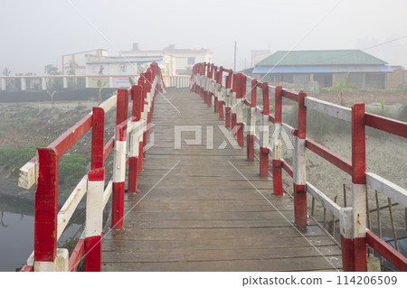 a traditional wooden local bridge near primary school at foggy morning 114206509