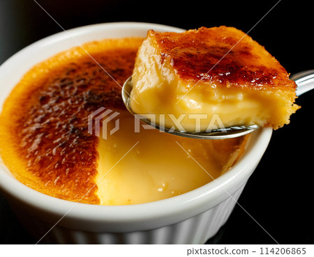 Crème brûlée scooped with a spoon on a black background 114206865