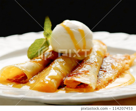 Crepes Suzette topped with vanilla ice cream 114207453