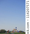 Playground equipment in a park under a wide blue sky 114207571