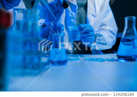 Medical or research scientist or doctor using looking at a test tube of clear solution in a lab or laboratory. 114208189