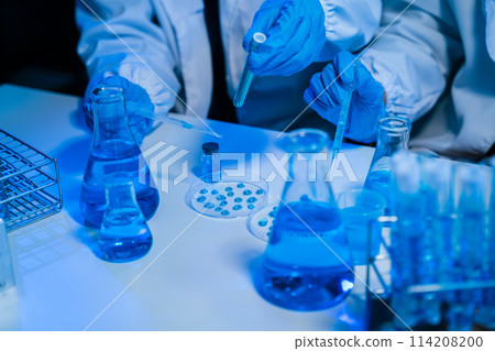 Medical or research scientist or doctor using looking at a test tube of clear solution in a lab or laboratory. 114208200