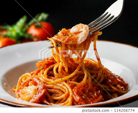 Tomato and seafood pasta held up by a fork on a black background Tomato and seafood pasta held up by a fork on a black background 114208774