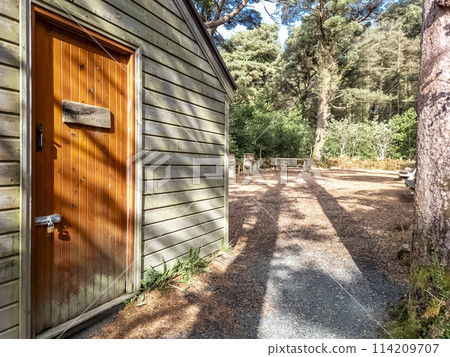 Wooden house in a forest in County Donegal - Ireland, Sign explaining in Irish and English: Nature Cabin 114209707