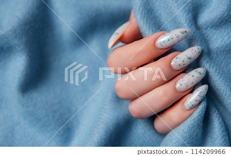 Female hands with blue nail design on blue textile background. 114209966