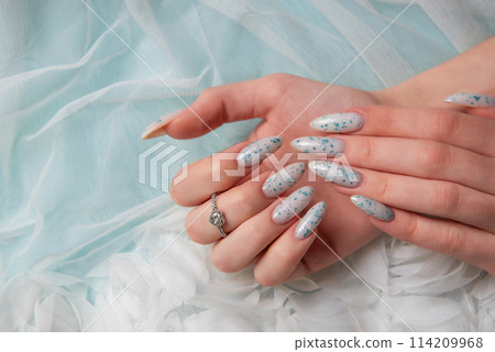 Female hands with blue nail design on blue silk background. Female hands with blue nail design on blue silk background. 114209968