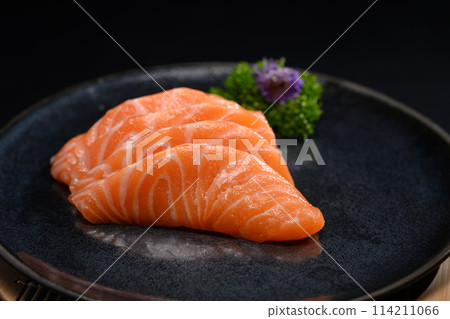 Salmon sashimi on black plate with parsley leaf. Japanese food style Salmon sashimi on black plate with parsley leaf. Japanese food style 114211066