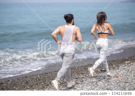Happy couple running together beside the water at the beach 114211698