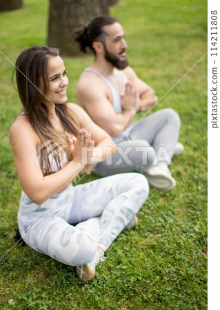 Young couple doing yoga outdoors Young couple doing yoga outdoors 114211808