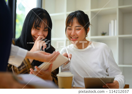 Cheerful college students working together project at library 114212037