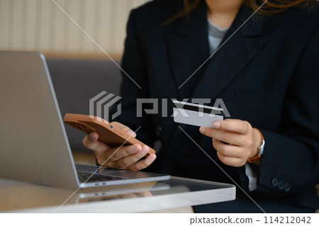 Young businesswoman with credit card doing online shopping on her smartphone Young businesswoman with credit card doing online shopping on her smartphone 114212042
