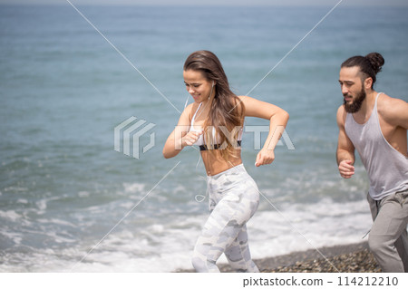 Happy couple running together beside the water at the beach 114212210