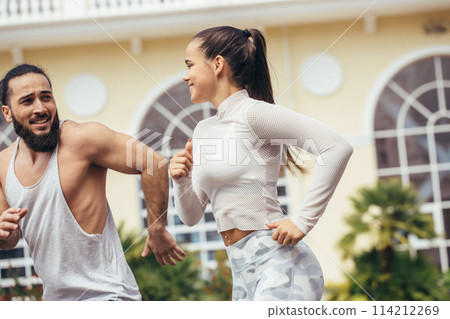 fitness, sport, people and lifestyle concept - happy couple with earphones running outdoors 114212269