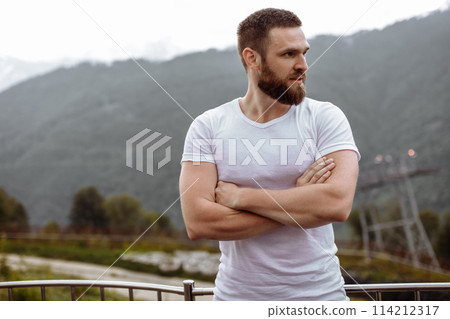 Handsome muscular hunk man looking at mountains from the peak. Handsome muscular hunk man looking at mountains from the peak. 114212317