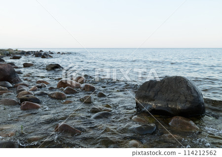 Summer evening on a lake shore with big stones 114212562