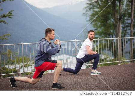 Side view of two caucasian sportsmen doing lunges in mountains. 114212707