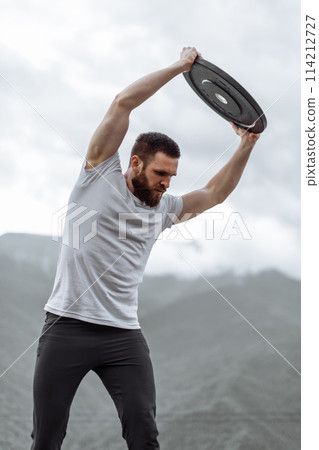 Handsome muscular hunk man looking at mountains from the peak. 114212727