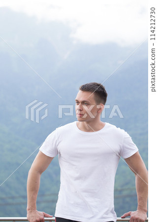 Handsome muscular hunk man looking at mountains from the peak. Handsome muscular hunk man looking at mountains from the peak. 114212730